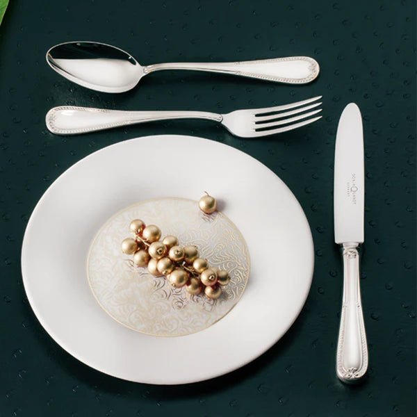 Dessert fork from Palmette collection by Sonja Quandt next to white plate.