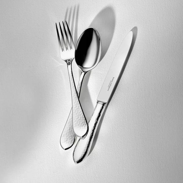 Martelé menu fork in silver plate with hammered texture next to fork and knife.