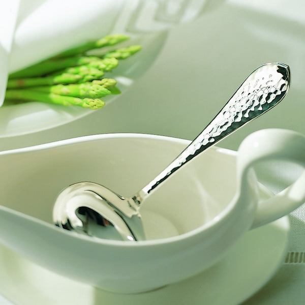 Martelé silver-plated sauce ladle  with hammered handle presented in sauce bowl.
