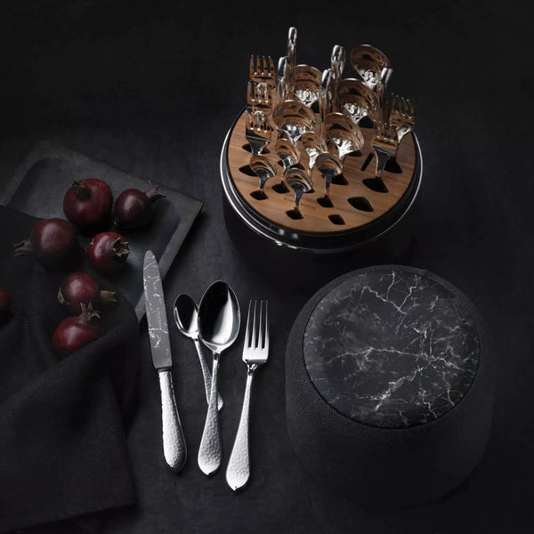 Martelé cutlery set with marble-finish DLC knives in marble box by Robbe & Berking styled on black table.