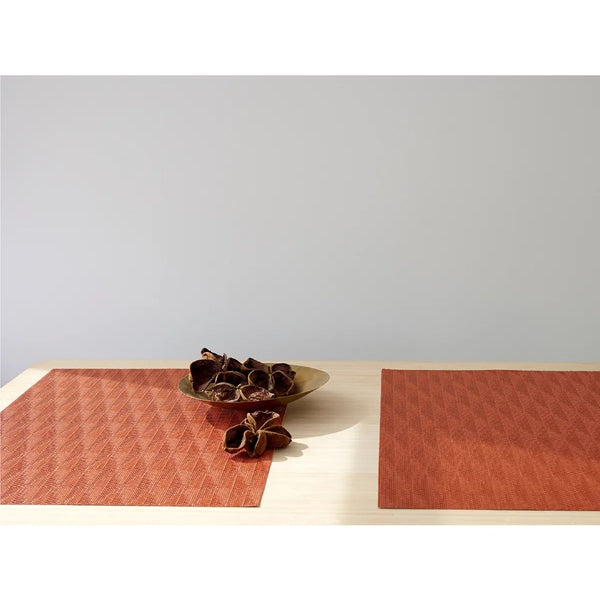 Chilewich Arrow placemat in orange with geometric pattern on minimalist table.