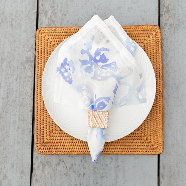 Beach-themed summer table with square rattan napkin ring in beige, white, and blue tones