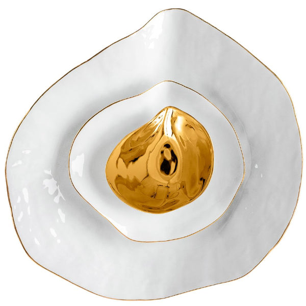 A set of white porcelain oyster-shaped dinnerware with gold detailing on the rim.