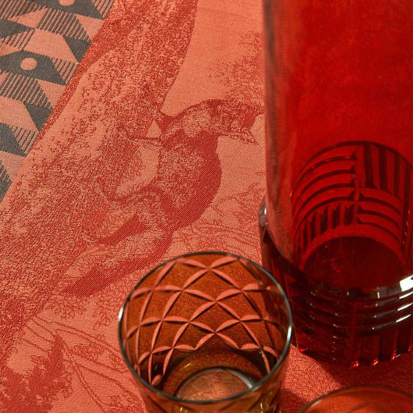 Orange cotton placemat with forest motifs and geometric border close-up.