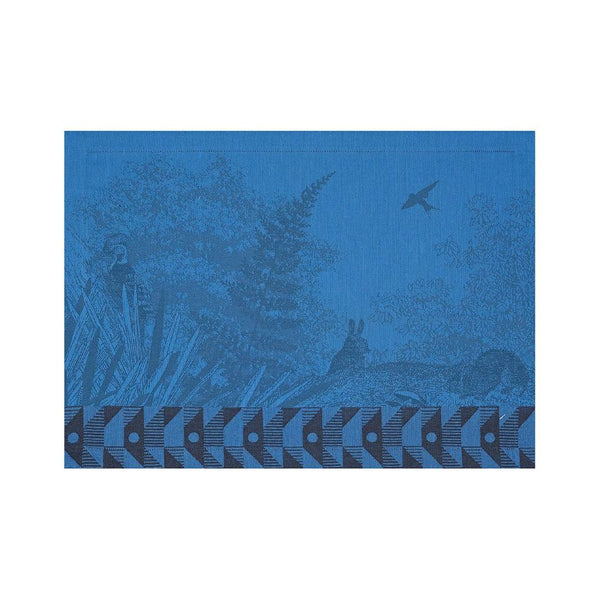 Blue cotton placemat with forest motifs and geometric border by Le Jaquard Francais.