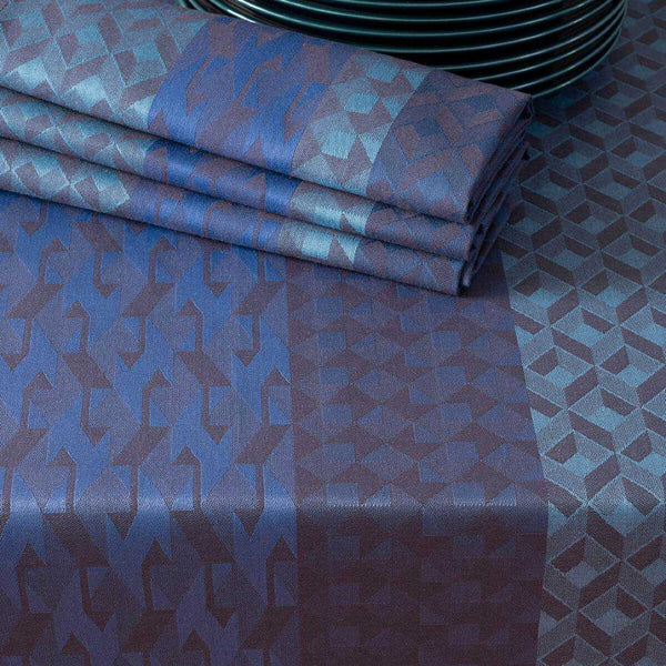 Blue coated cotton placemat with retro  graphics folded on matching tablecloth.