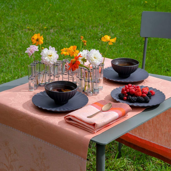 Coral linen napkin by Le Jacquard Français styled on outdoor table setting, sold at Amiramour.
