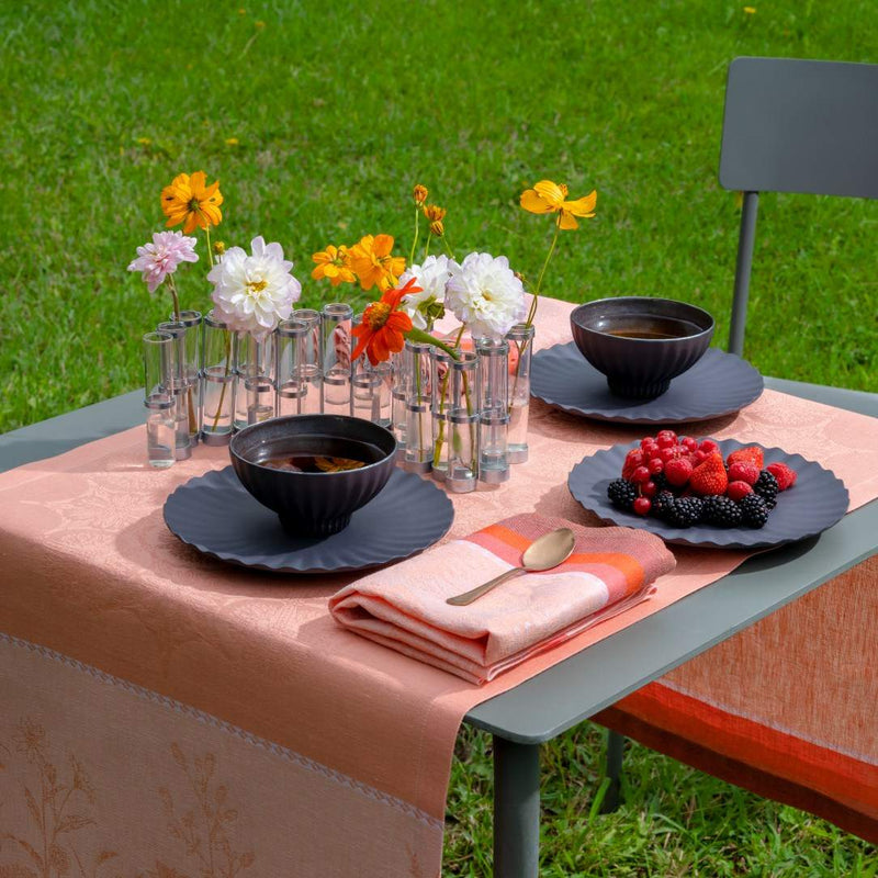 Coral linen napkin by Le Jacquard Français styled on outdoor table setting, sold at Amiramour.