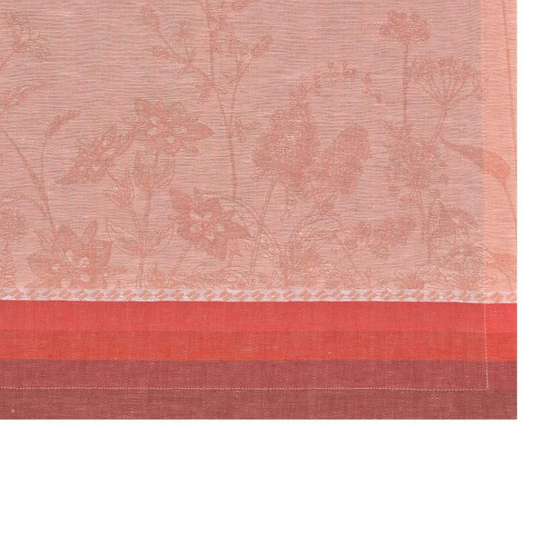 Pink red linen placemat with jacquard floral motifs in soft tones close up.