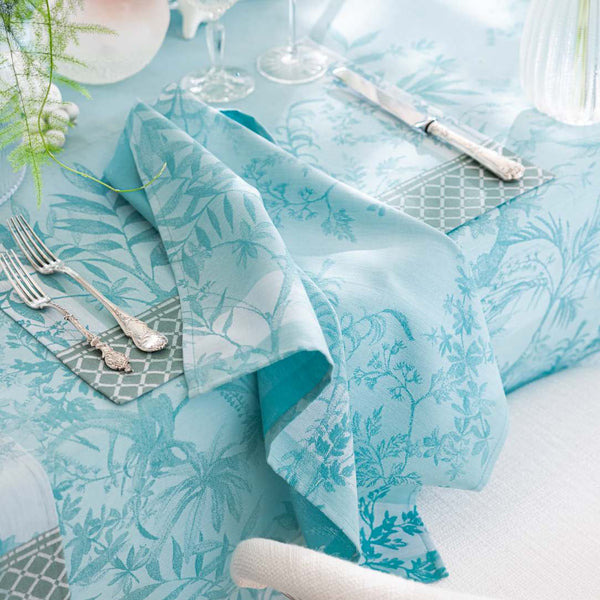 Blue Jardin d’Eden cotton napkin with delicate floral pattern styled on placemat and tablecloth from the same collection.