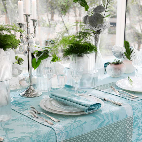 Blue cotton placemat with botanical jacquard ivy and calathea motifs side view.