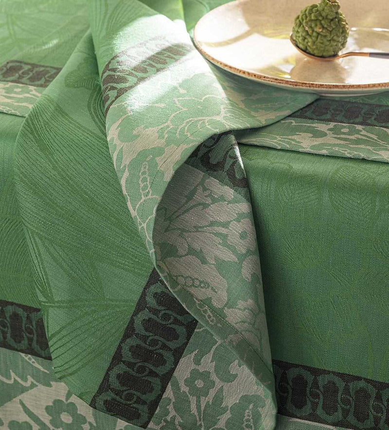 Close-up of Escapade Tropicale linen napkin in green by Le Jaquard Francais on tablecloth from the same collection.