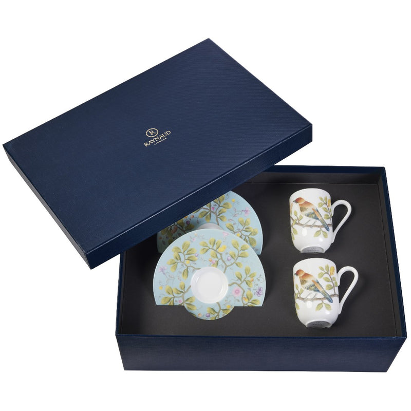 A set of two espresso cups and saucers with turquoise and multicolor floral patterns, presented in a navy blue gift box with the Raynaud brand logo.