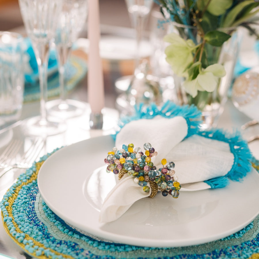 Close-up of pastel beaded napkin ring in turquoise table setting by Kim Seybert