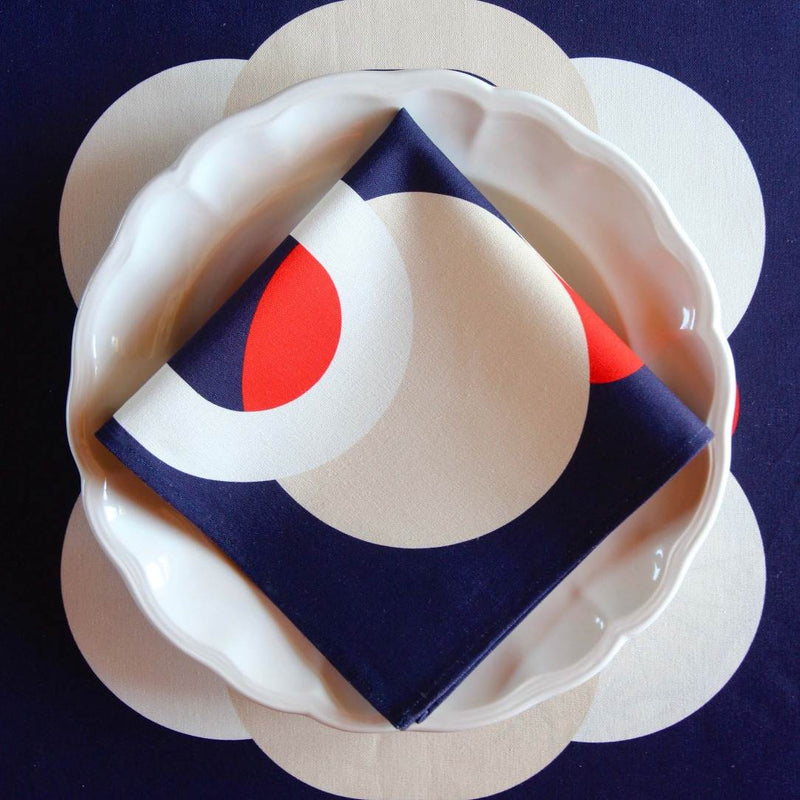Bubble Navy napkin with vibrant red, white, and ivory 70s-inspired bubble motifs folded on plate.