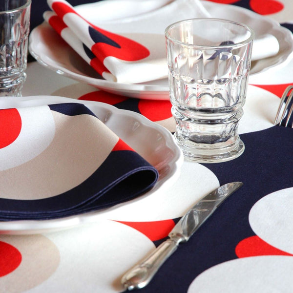 Bubble Navy napkin with vibrant red, white, and ivory 70s-inspired bubble motifs folded on plate.