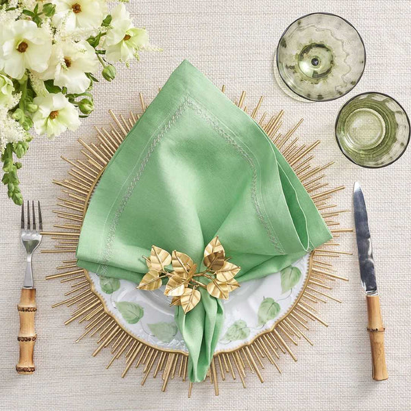 Gold sunburst Radiate charger plate by Kim Seybert styled with green napkin.