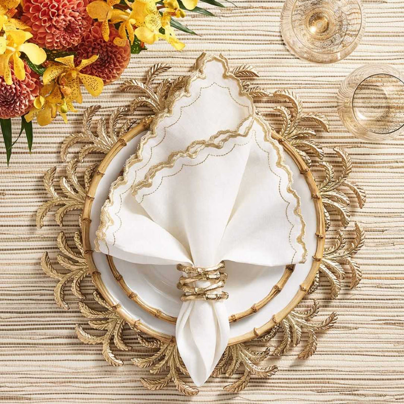 Gold Palmera charger with raised palm fronds and trunk texture styled on luxury tablescape.