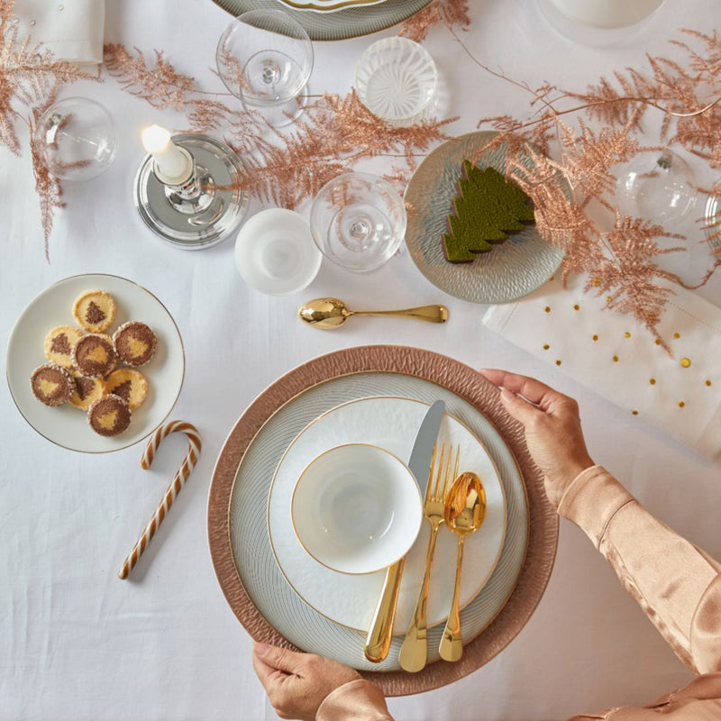 Ercuis Baguette gold-plated dinner knife with polished blade and golden handle on white dinner plate.