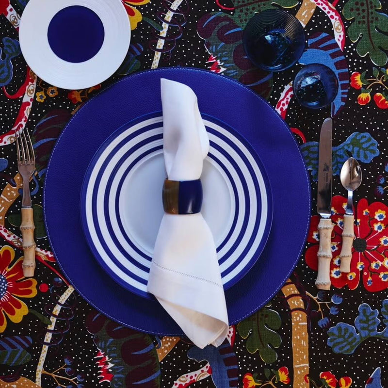 Reversible placemat in blue and white faux leather styled on colourful tablescape.