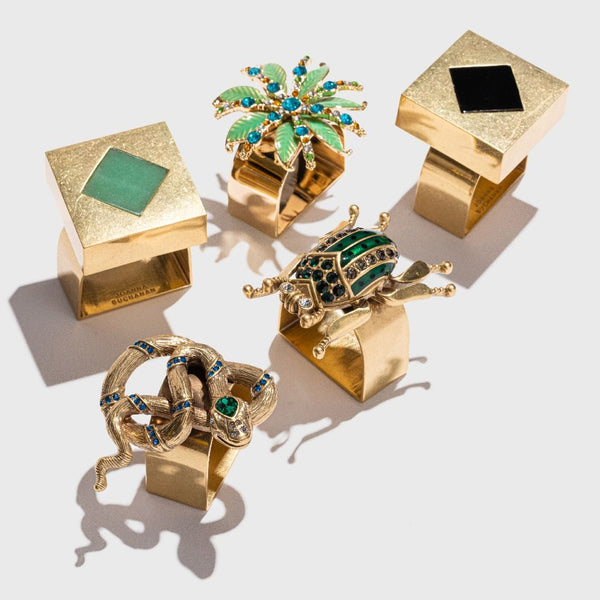 Palm tree napkin ring next to other gold napkins from Joanna Buchanan.