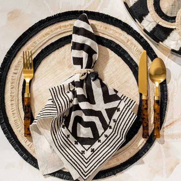 Beige and black Ruffle Edge Straw Placemats with handwoven texture styled with blad white napkin.