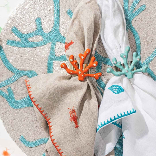 Turquoise coral placemat with intricate detailing with coral napkin rings.