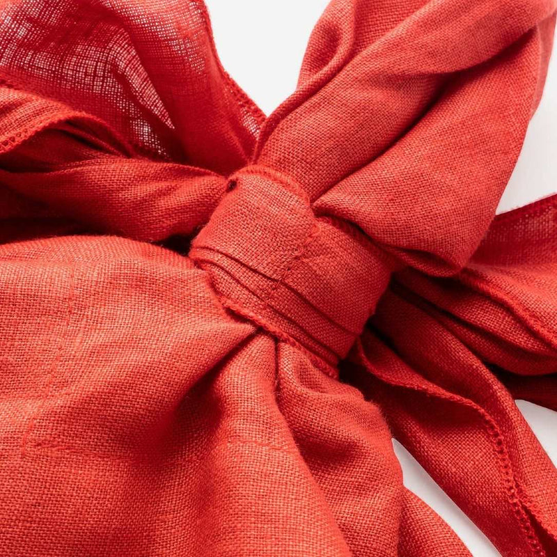 Close-up of pre-tied red linen napkin in a bow shape by Joanna Buchanan .