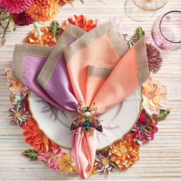 Linen napkin in lilac and soft orange by Kim Seybert styled on floral placemat.