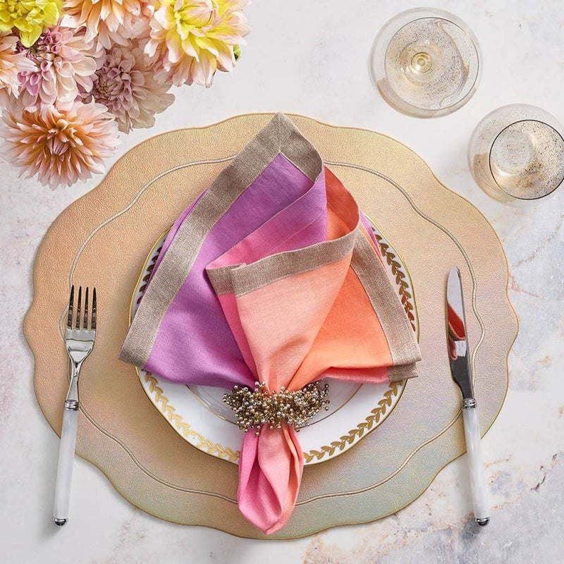 Linen napkin in lilac and soft orange by Kim Seybert styled on gold placemat.