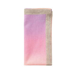 Linen napkin in lilac and soft orange by Kim Seybert folded on white background.