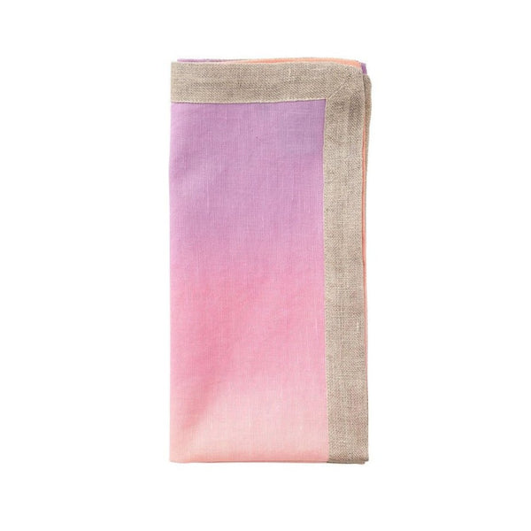 Linen napkin in lilac and soft orange by Kim Seybert folded on white background.