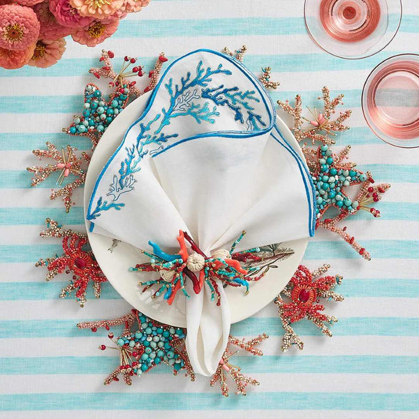 Kim Seybert Reef napkin on marine-inspired table setting with coral and turquoise accents.