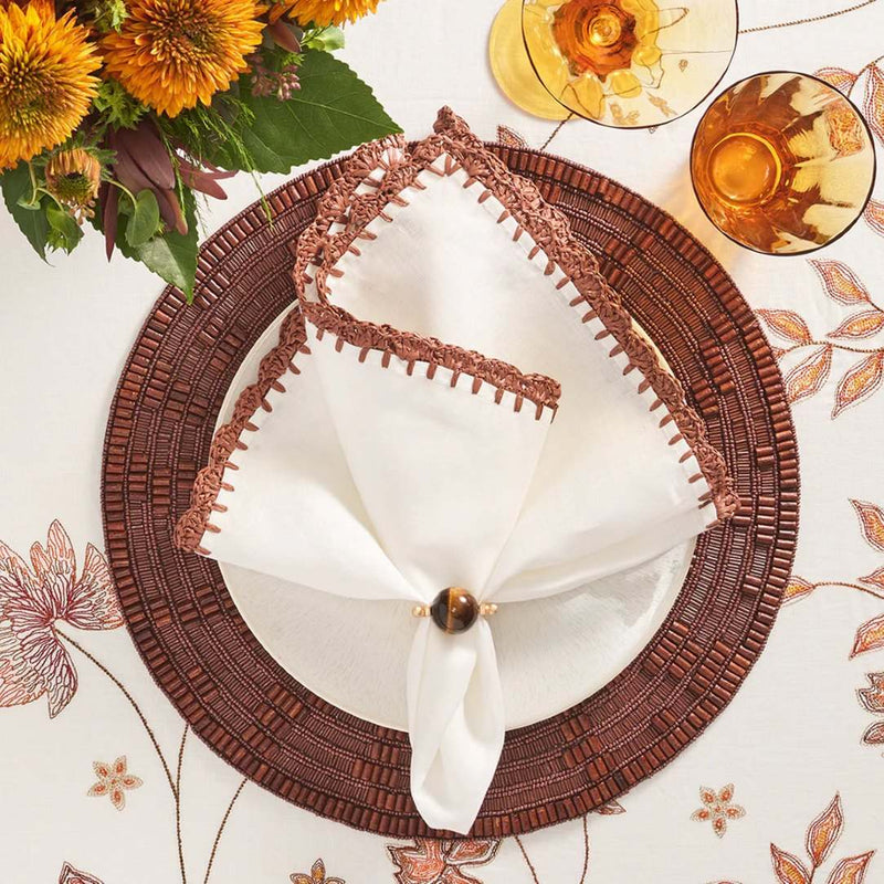 Shell Edge Napkin by Kim Seybert styled on brown placemat, top view, available at Amiramour