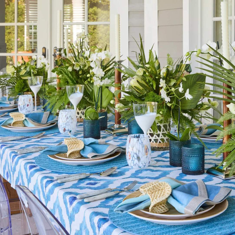 Side view of Blue Watercolor Ikat linen napkin by Kim Seybert styled on coastal tropical table setting, sold at Amiramour.