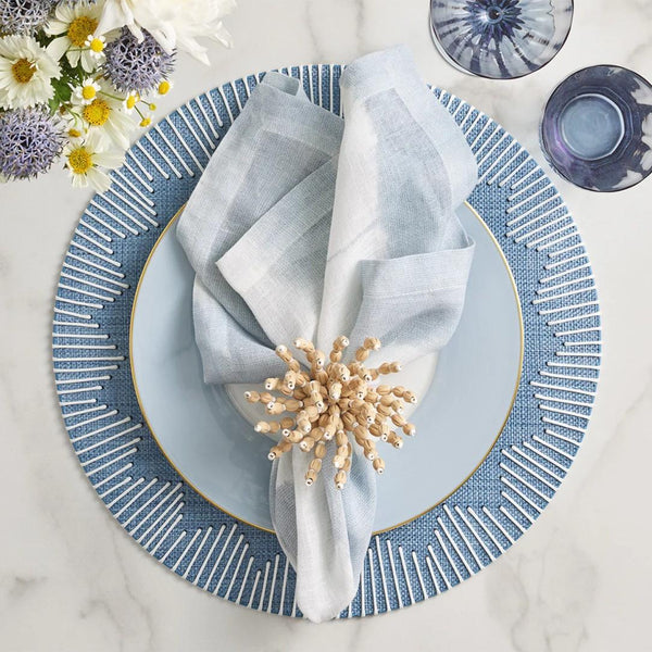 Watercolor stripe napkin in white, blue, and grey tones by Kim Seybert styled on blue placemat