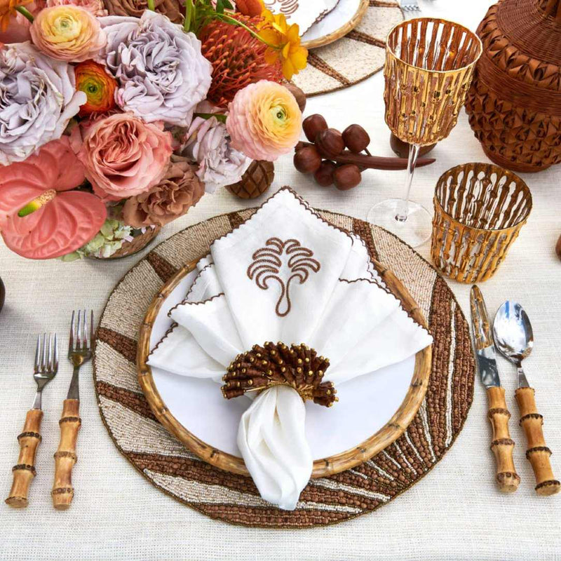 Top view of Royal Palm napkin styled on elegant tropical table setting in white and earth tones by Amiramour