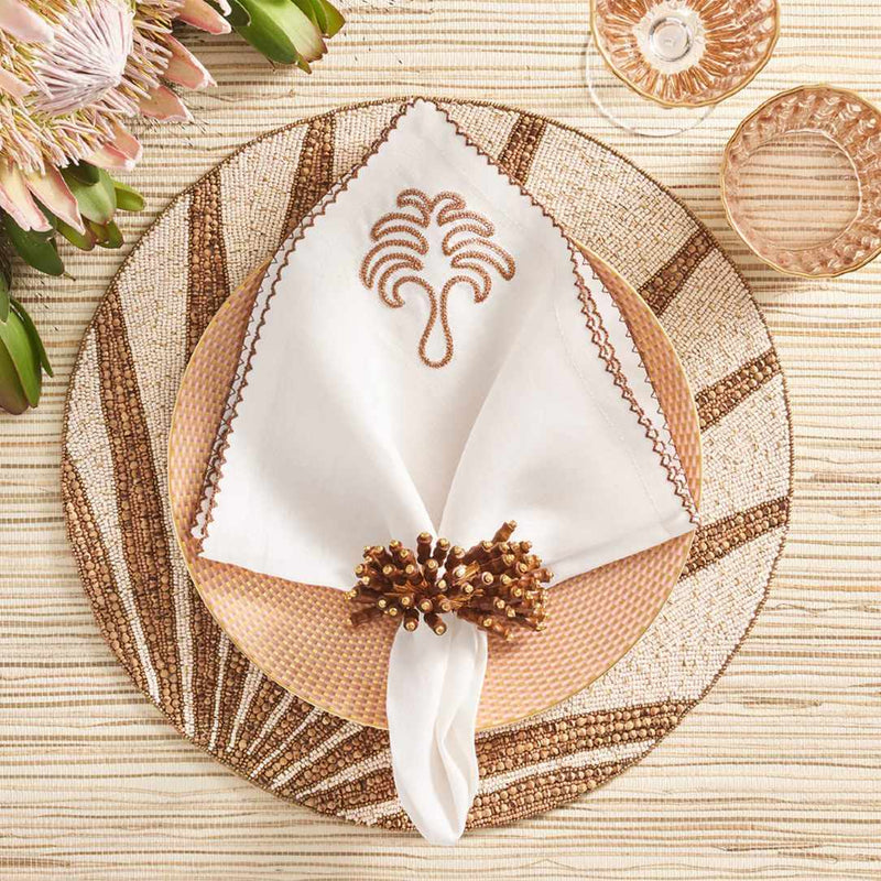 Kim Seybert Royal Palm napkin on a natural, tropical tablescape with wood and linen textures