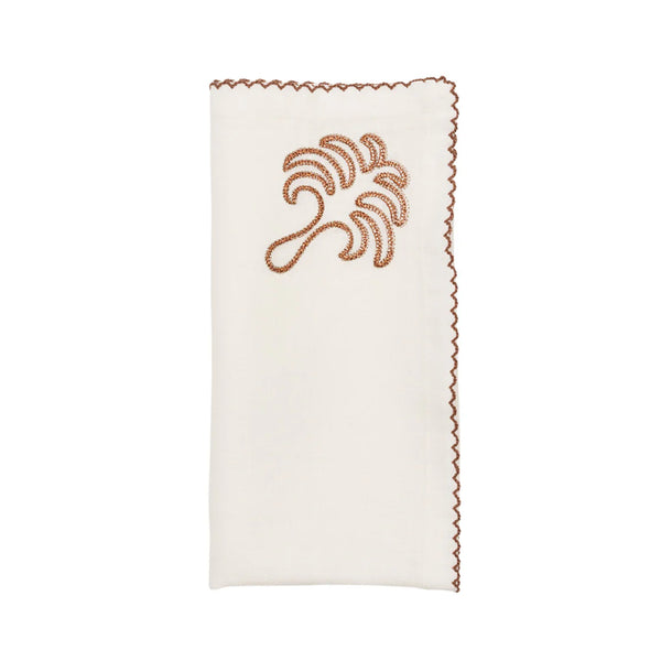 Folded Royal Palm napkin in white linen with brown tropical embroidery by Kim Seybert, available at Amiramour