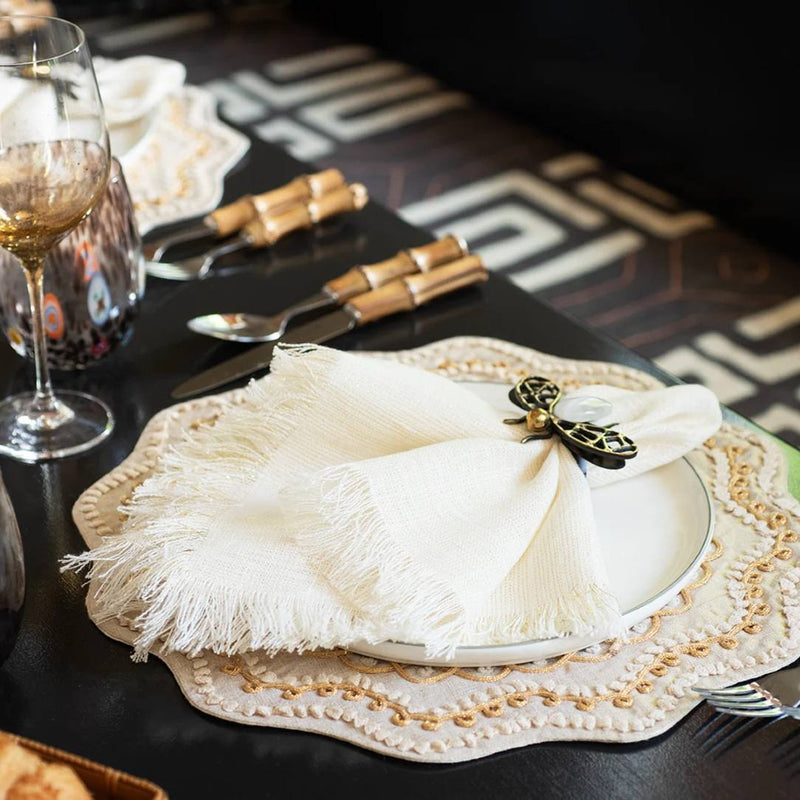 Fringe napkin in white and gold on a modern casual table setting with warm neutrals, side view 