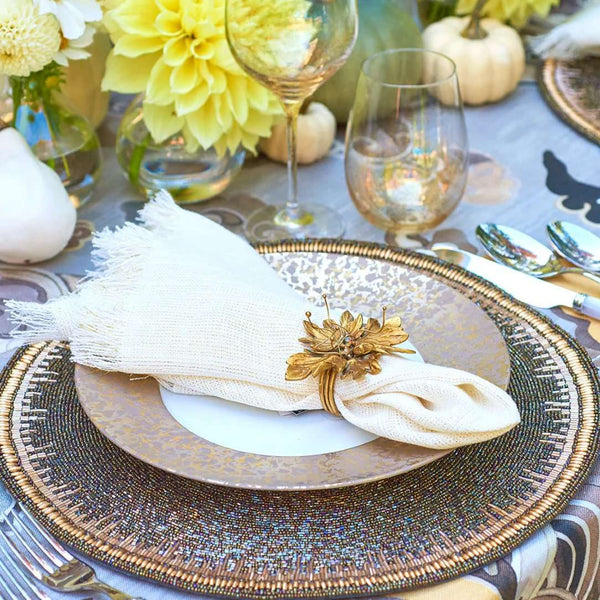 Fringe napkin in white and gold styled on an autumnal table with warm tones flowers and pumpkins, side view