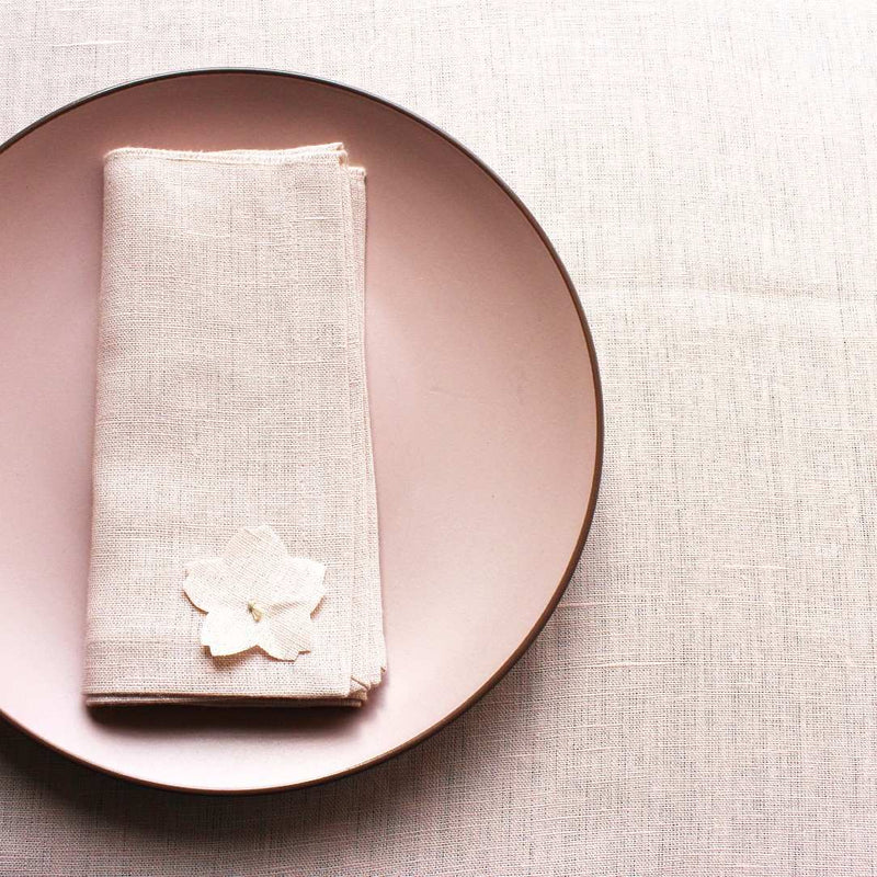 Close-up of cherry blossom detail on light pink linen napkin – Amiramour