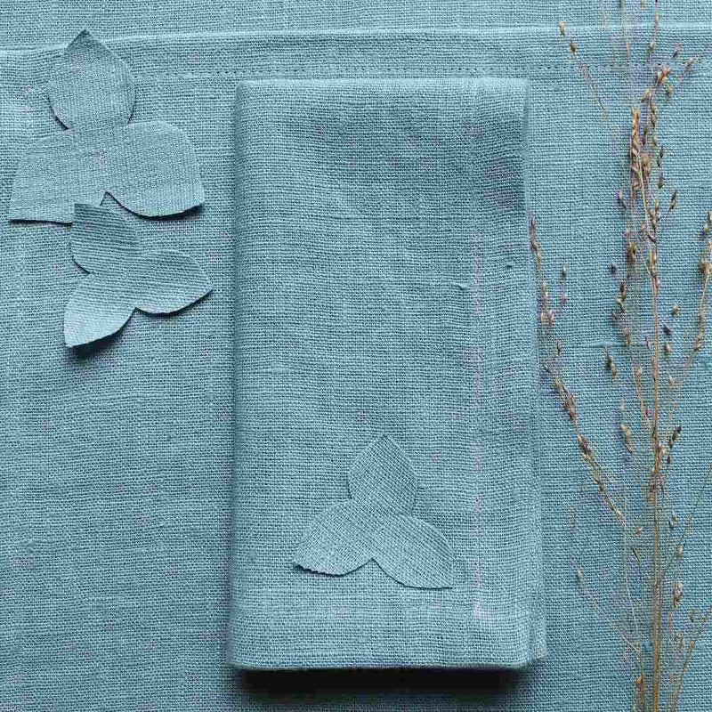 Sky blue linen napkin with hydrangea appliqué, on placemat from the same collection, sold at Amiramour.