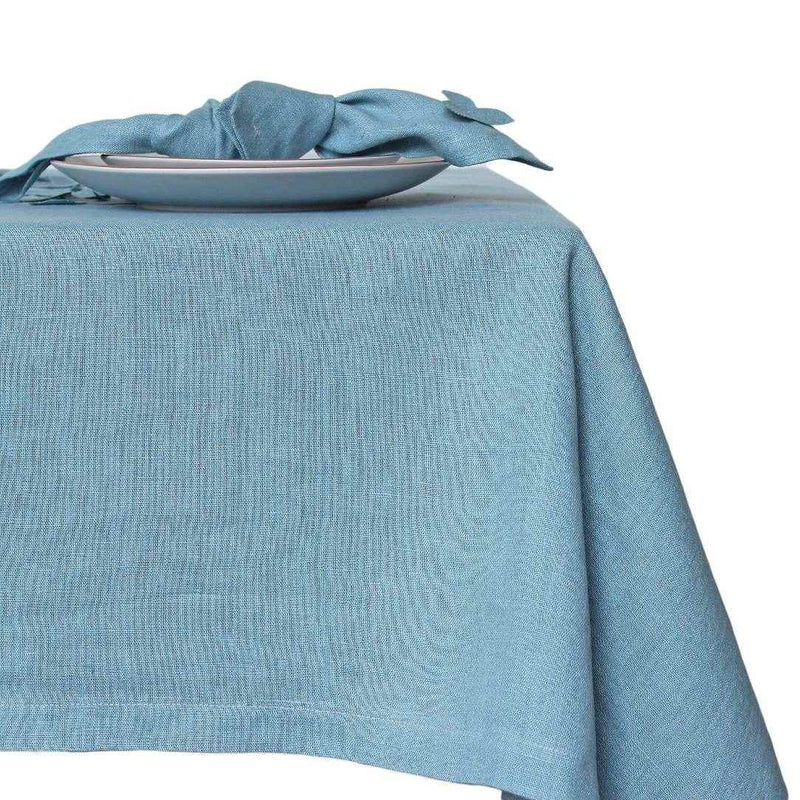 Side view of sky blue linen napkin with hydrangea appliqué, on tablecloth from the same collection, sold at Amiramour.