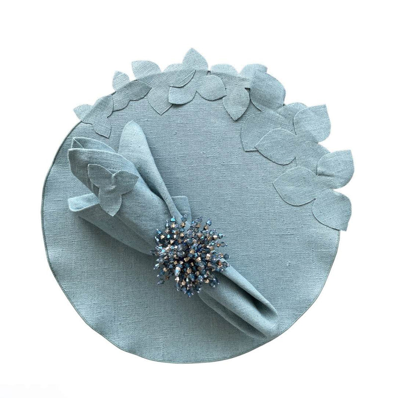 Sky blue linen napkin with hydrangea appliqué by Giardino Segreto, styled on round hydrangea placemat.