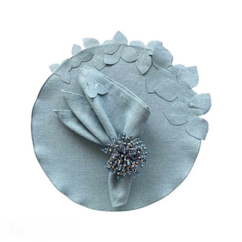 Sky blue linen napkin with hydrangea appliqué, styled with shiny blue napkin ring, sold at Amiramour.