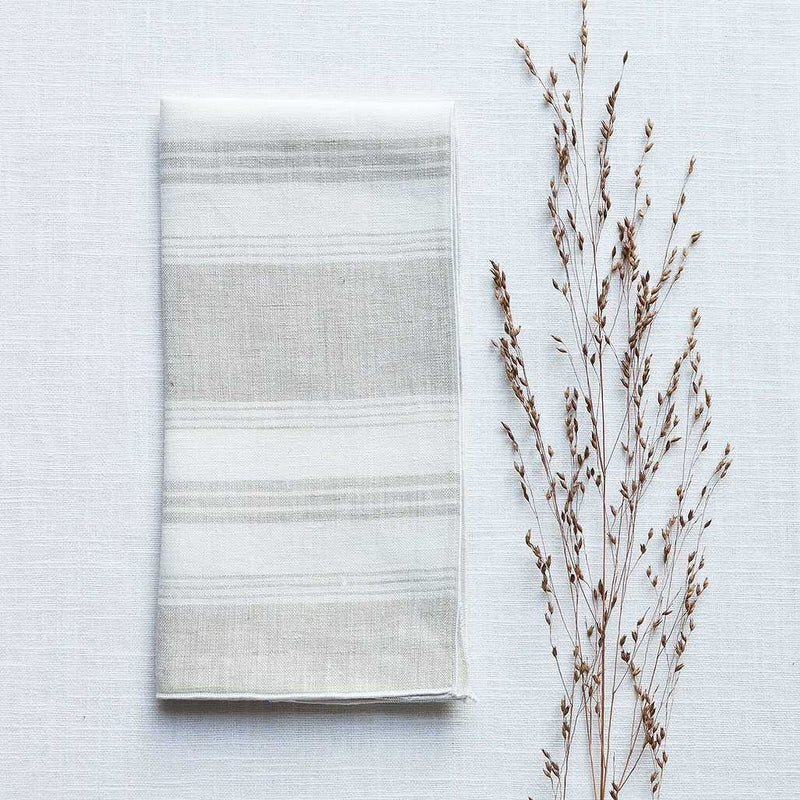 Riva beige striped linen napkin styled on minimalist white background