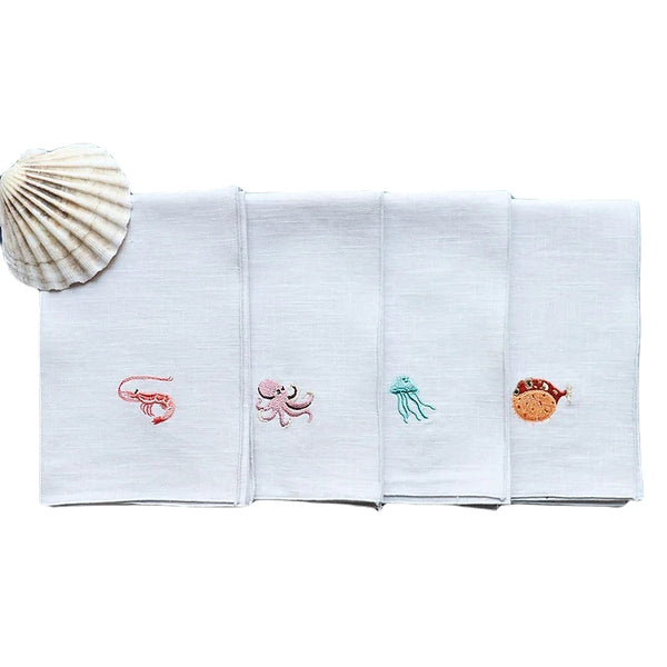 Folded Marina linen napkins embroidered with sea creature, white background sold on Amiramour