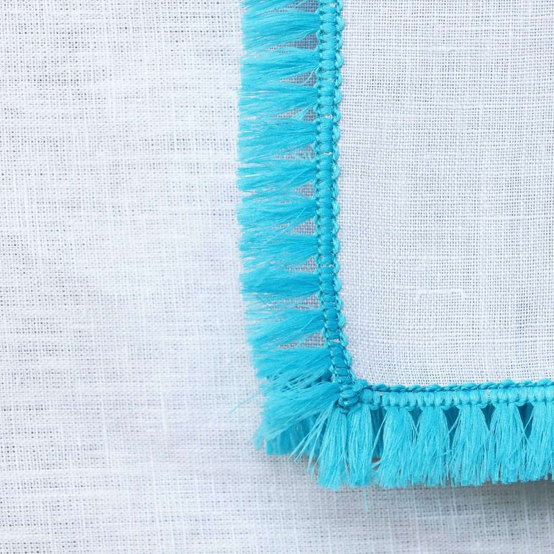 Close-up of turquoise fringe detailing on the Santorini napkin by Kim Seybert, sold at Amiramour.