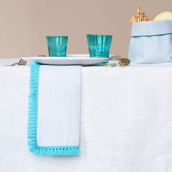 Close-up of turquoise fringe detailing on the Santorini napkin styled on mediteranean simple table.